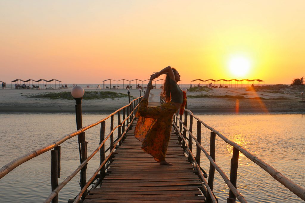 Mujer practica yoga en una playa de Goa