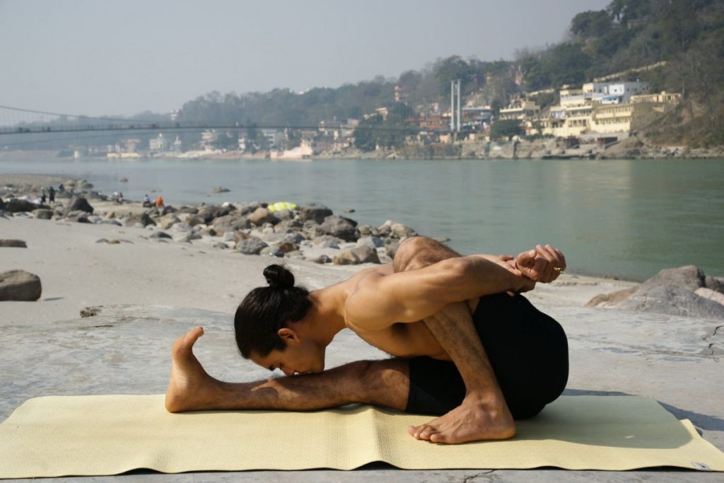 Practicante de yoga junto al río Ganges en Rishikesh 