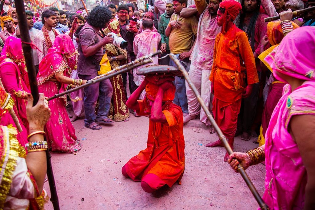 Mujeres golpeando con un palo a un hombre en Holi en Brindavan. 