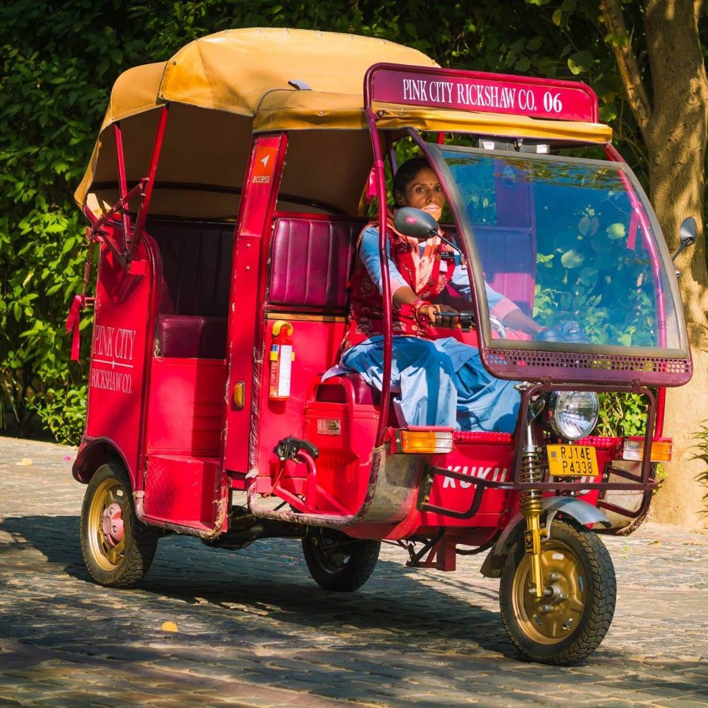 Mujer conduciendo un rickshaw rosa en Jaipur 