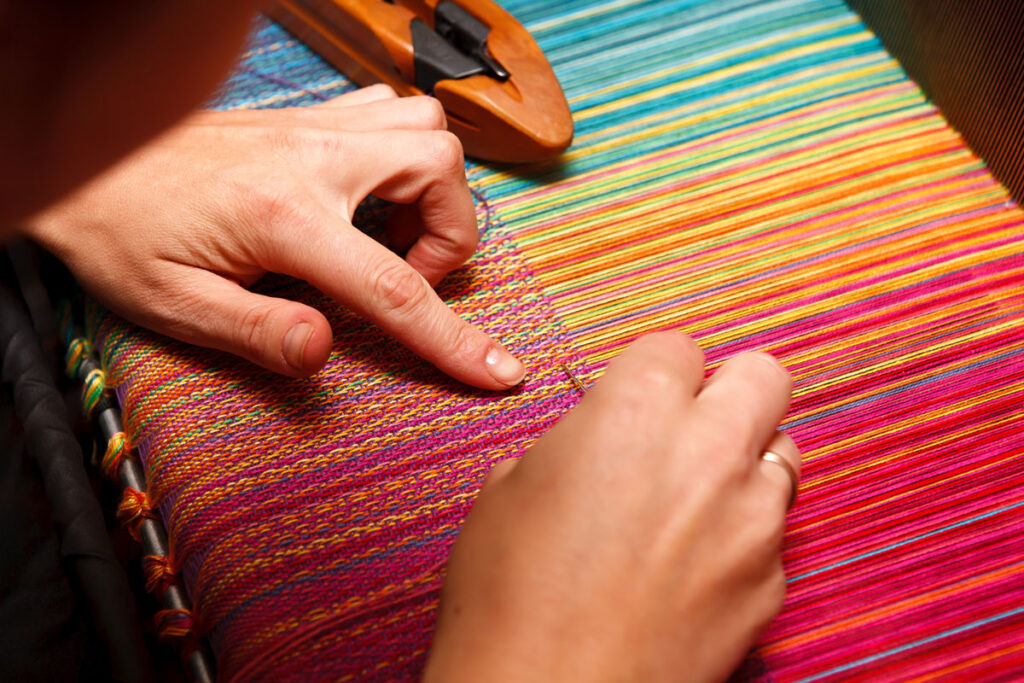Mujer bordando hilos de colores en Bután.