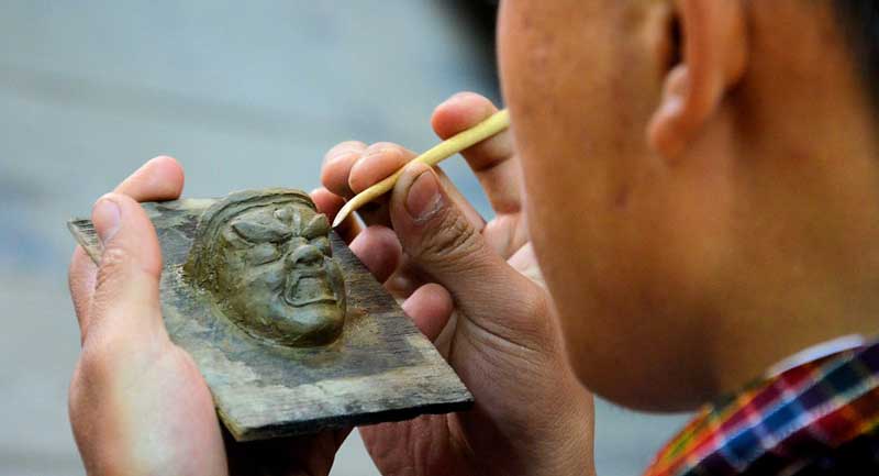 Artesano esculpiendo una figura en Bután 