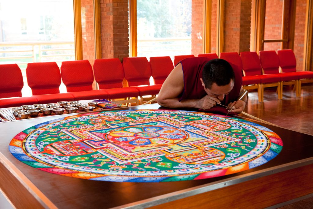 Monje tibetano trabajando en un mandala de arena