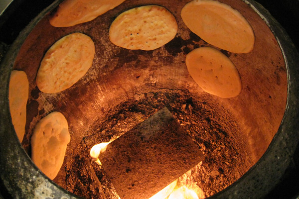 Pan naan cocinándose en un horno tandoor