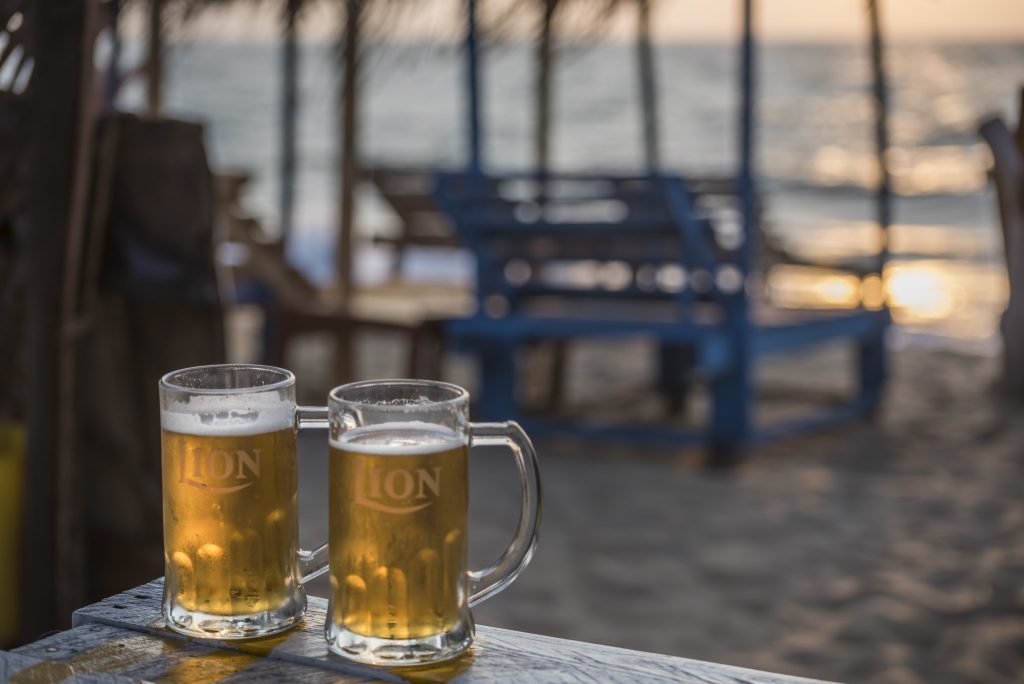Dos jarras de cerveza Lion en una mesa en la playa